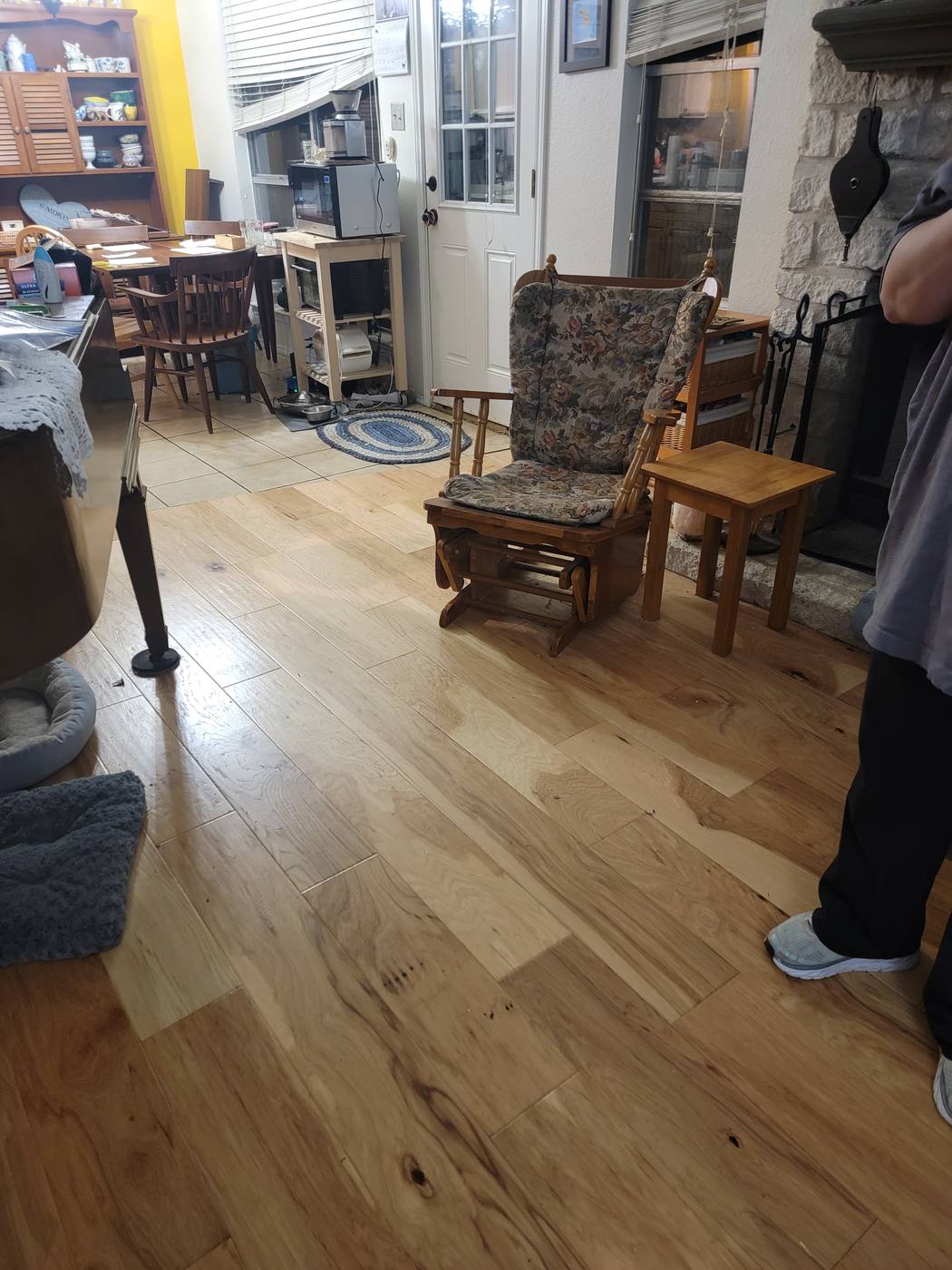 A living room floor covered with bags and loose belongings, then the same room with clear floors and furniture back in place