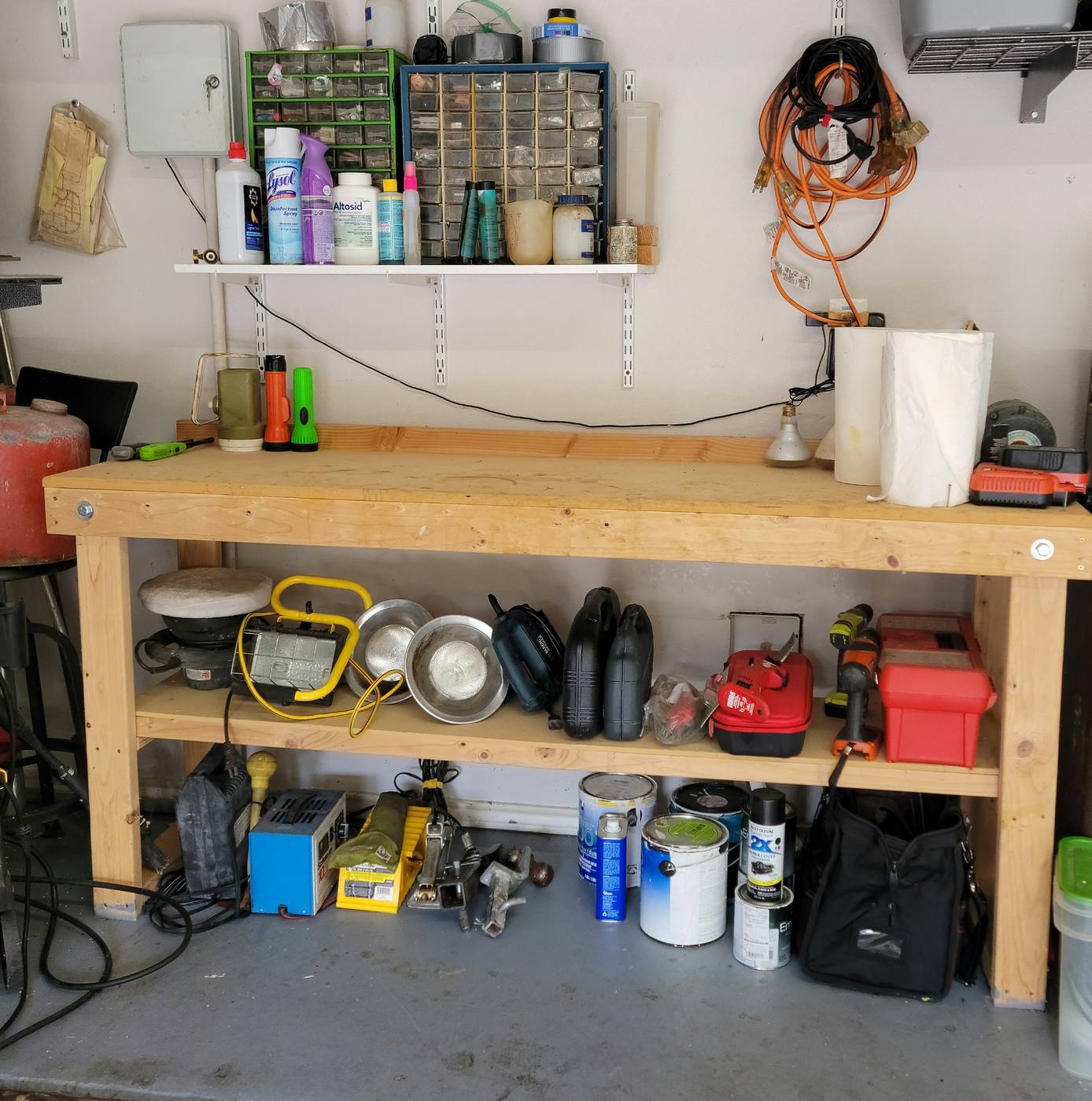 A garage workbench buried under tools and supplies, then the same bench with tools mounted and containers on labeled shelves
