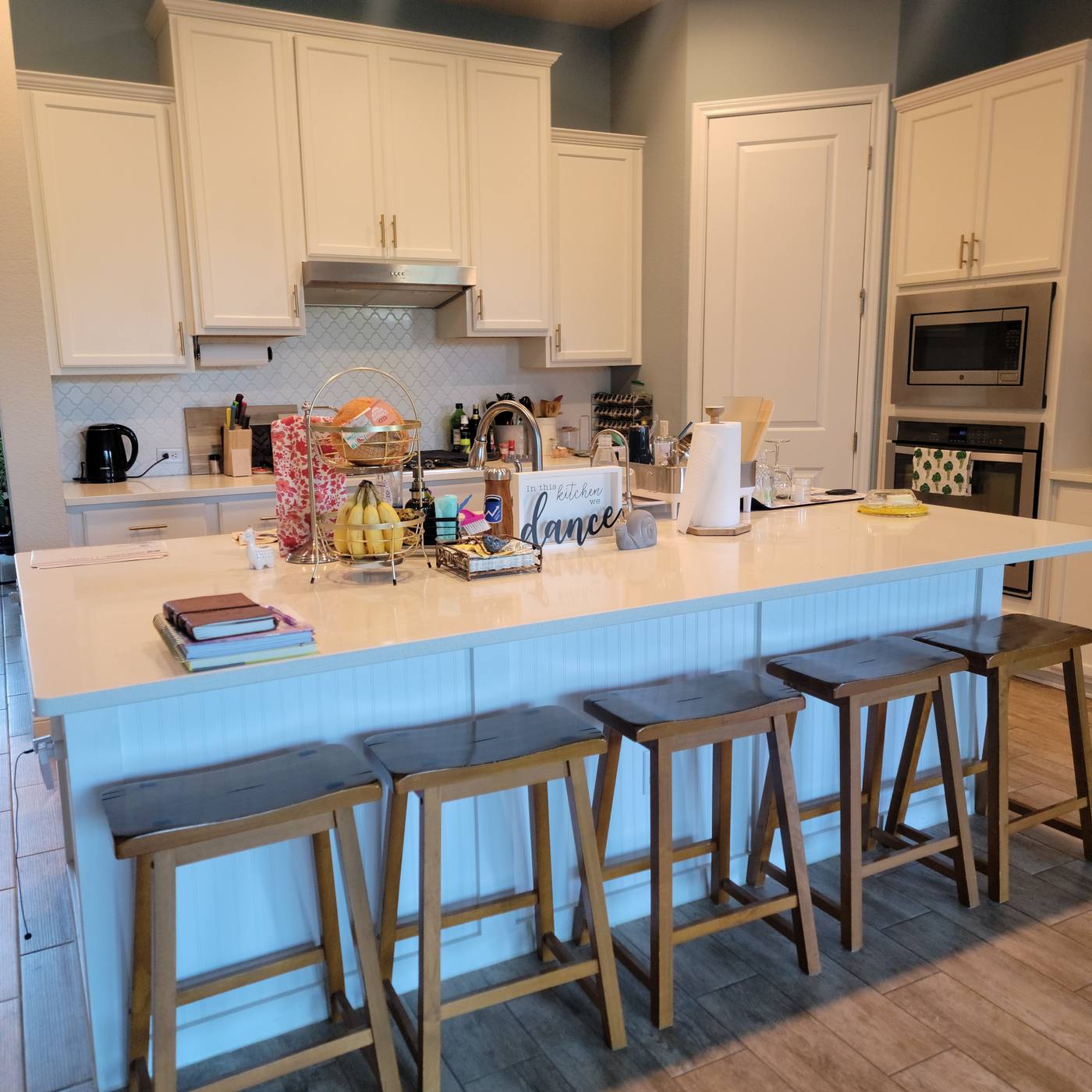 A kitchen island covered end to end with mail, bags and clutter, then the same island cleared down to a few intentional items
