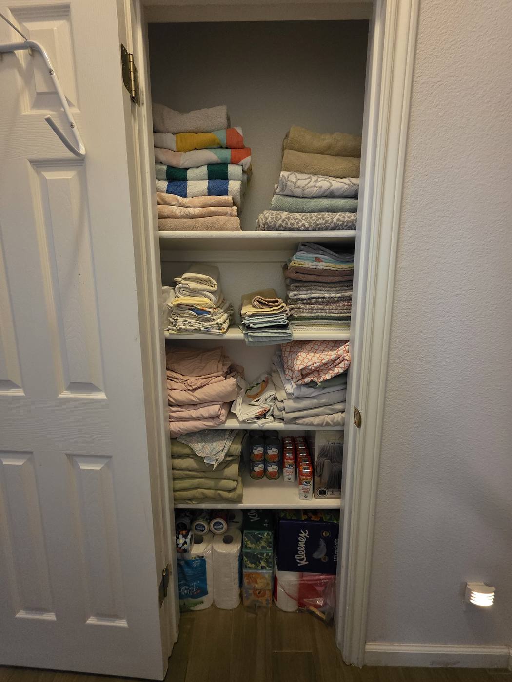 A linen closet with towels and bedding stuffed in unevenly, then the same closet with everything folded and stacked by type