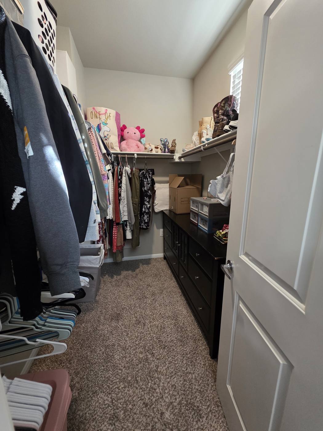 A primary closet overflowing onto the floor, then the same closet with clothes hung by category and clear walking space
