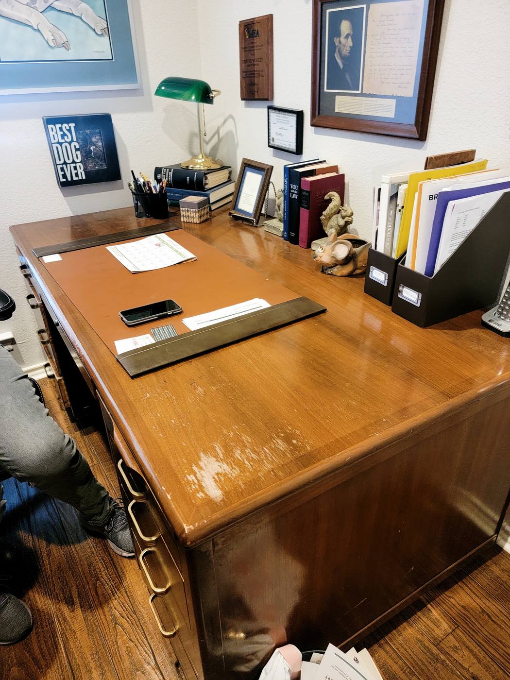 A wooden desk covered with papers, photos and mail, then the same desk cleared with a blotter and sorted upright files